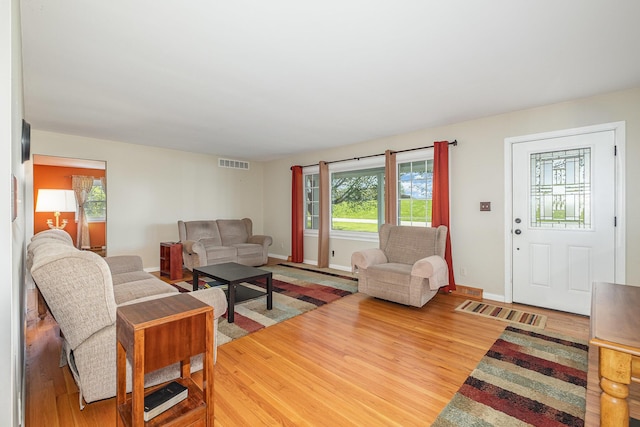 living room with baseboards, visible vents, and wood finished floors