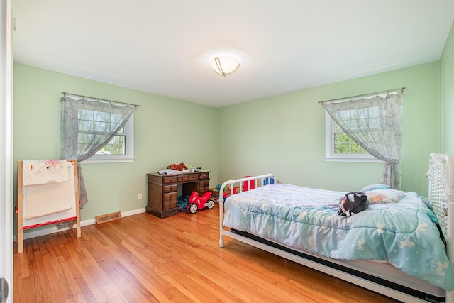 bedroom with baseboards, multiple windows, light wood-type flooring, and visible vents