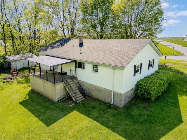 back of house with a chimney, stairway, an outdoor structure, a yard, and a shingled roof