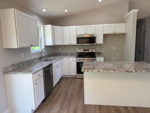 kitchen featuring white cabinets, light stone countertops, appliances with stainless steel finishes, and a sink