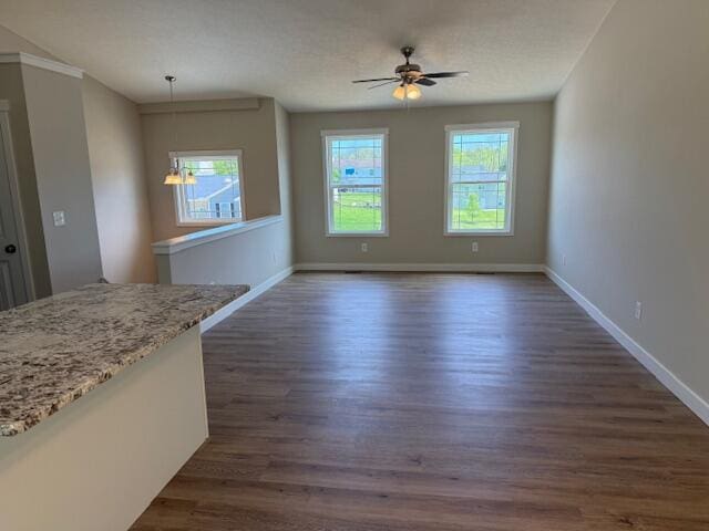 unfurnished living room with baseboards, ceiling fan, and dark wood-type flooring