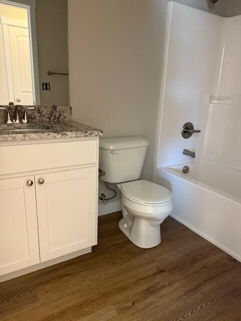 bathroom with shower / bath combination, wood finished floors, baseboards, vanity, and toilet