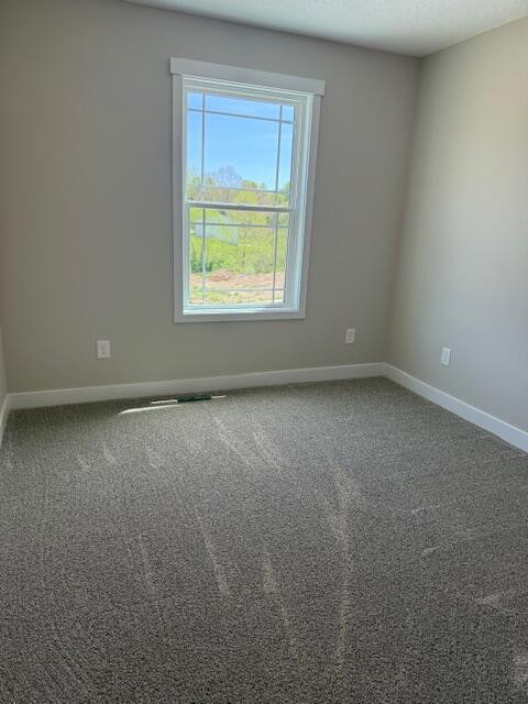 unfurnished room featuring baseboards and carpet