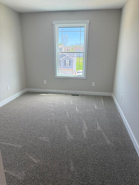 carpeted empty room with baseboards and visible vents