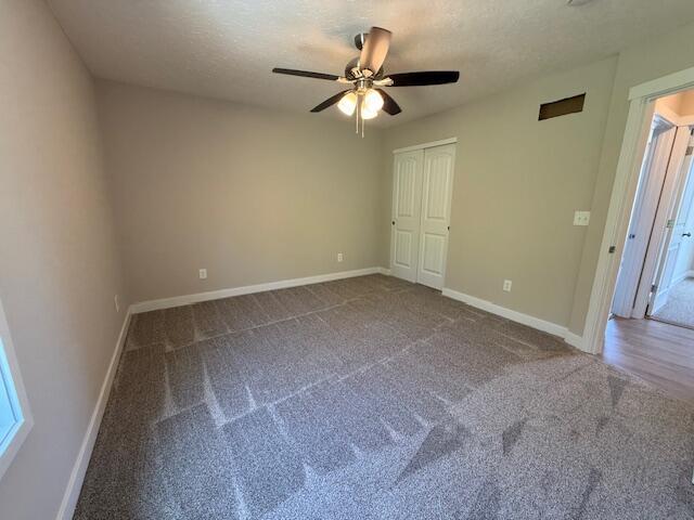 unfurnished bedroom featuring ceiling fan, a textured ceiling, carpet floors, baseboards, and a closet
