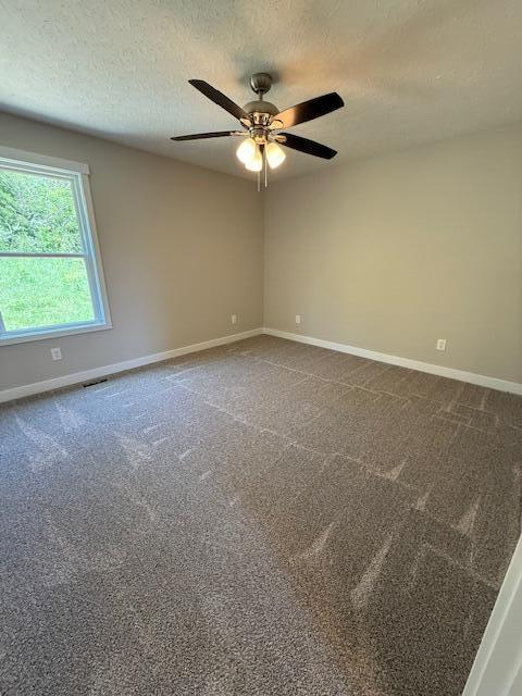 empty room featuring baseboards, carpet, a textured ceiling, and ceiling fan