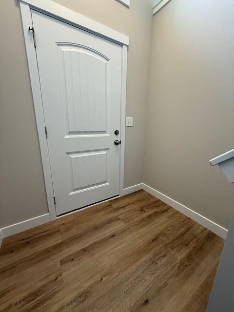 doorway to outside with baseboards and wood finished floors