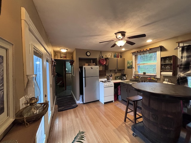 kitchen with white electric range oven, ceiling fan, gray cabinets, light wood-style flooring, and freestanding refrigerator