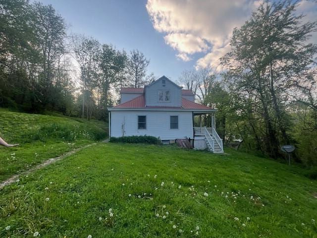 rear view of property featuring a lawn, stairs, and covered porch