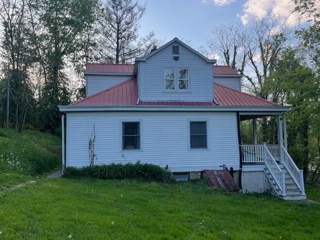 rear view of house with a yard, metal roof, and a porch