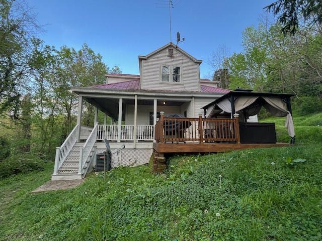 back of house featuring a lawn, stairway, and metal roof