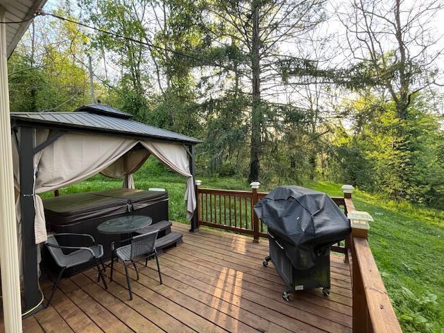 wooden deck featuring a gazebo, a hot tub, and area for grilling