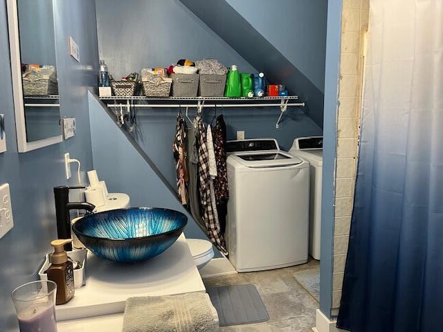 clothes washing area featuring a sink, laundry area, and washer and clothes dryer