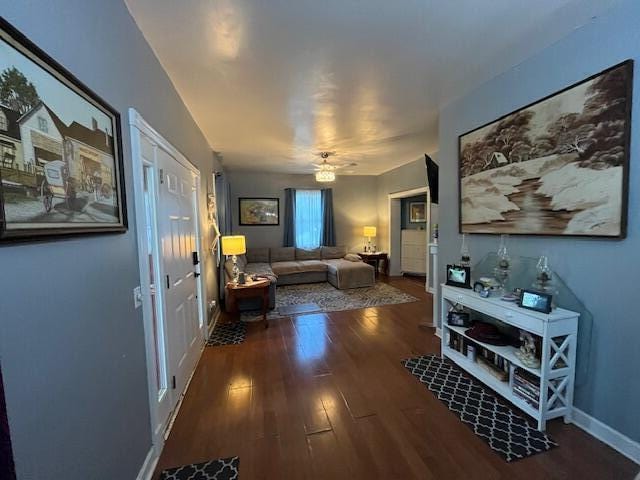 living area with a ceiling fan, baseboards, and wood finished floors