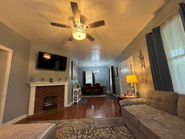 living room featuring a ceiling fan, baseboards, wood finished floors, and a fireplace