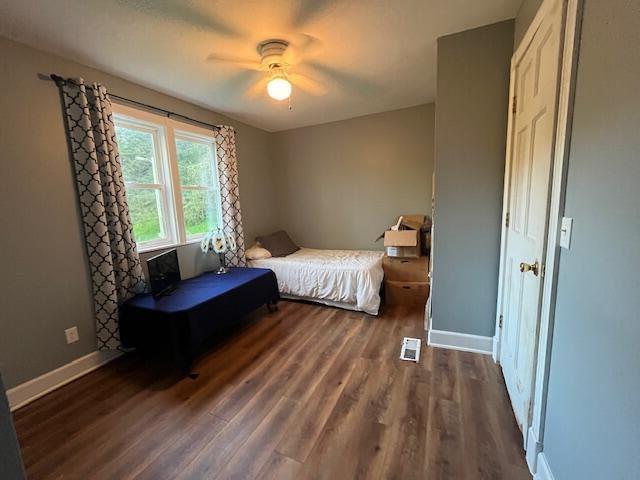 bedroom featuring visible vents, a ceiling fan, dark wood-style flooring, and baseboards