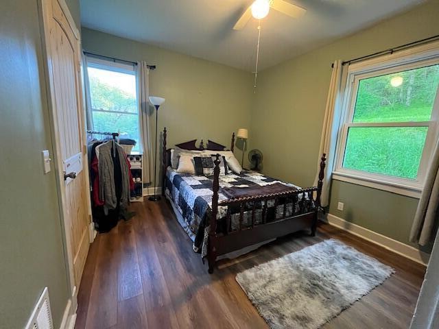 bedroom featuring baseboards, ceiling fan, wood finished floors, and visible vents