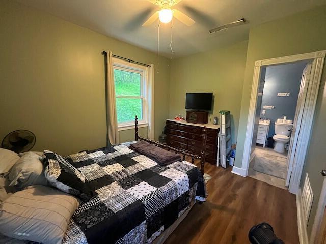 bedroom with baseboards, a ceiling fan, connected bathroom, and dark wood-style floors