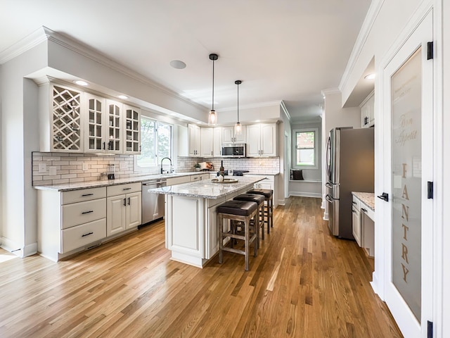 kitchen with appliances with stainless steel finishes, a center island, a breakfast bar, and light wood finished floors