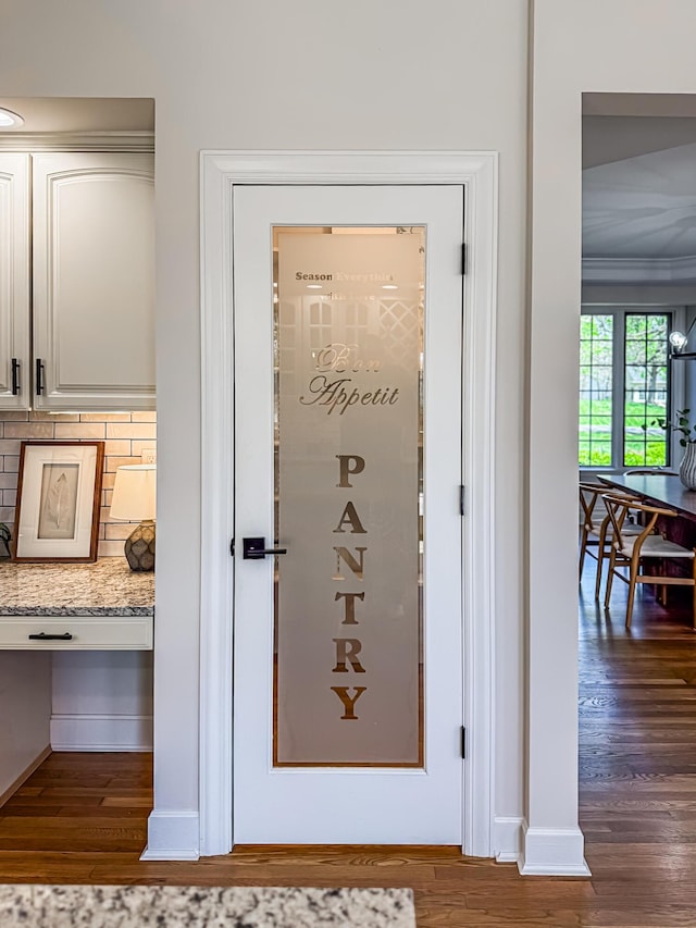 interior space with crown molding, baseboards, backsplash, and wood finished floors