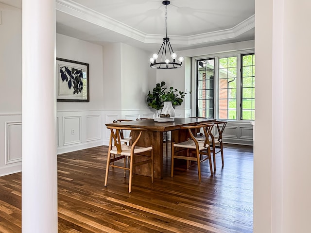 dining room featuring ornate columns, ornamental molding, dark wood-style flooring, and a notable chandelier