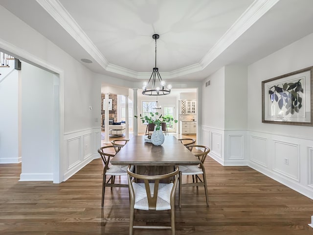 dining area featuring visible vents, crown molding, a decorative wall, dark wood-type flooring, and a raised ceiling