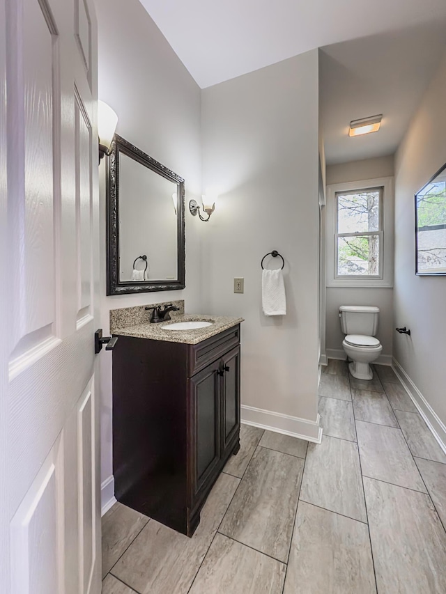 bathroom featuring vanity, baseboards, and toilet