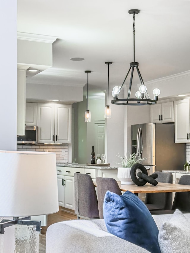 kitchen with crown molding, a chandelier, stainless steel appliances, and tasteful backsplash