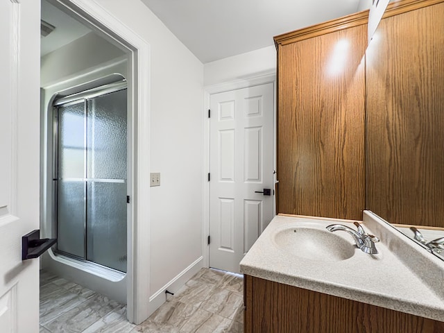 full bath with vanity, baseboards, and a stall shower