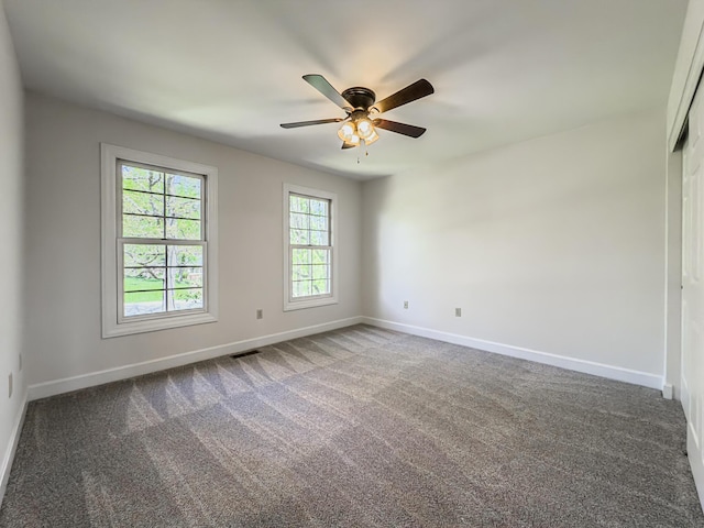 carpeted spare room featuring baseboards, ceiling fan, and visible vents