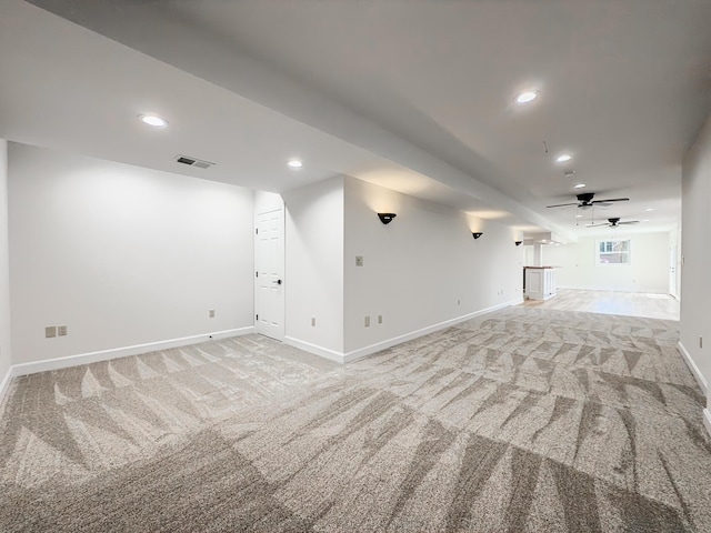 basement featuring light colored carpet, a ceiling fan, baseboards, recessed lighting, and visible vents