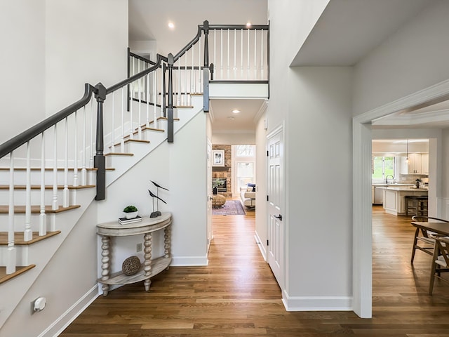 entrance foyer with a towering ceiling, wood finished floors, and a healthy amount of sunlight