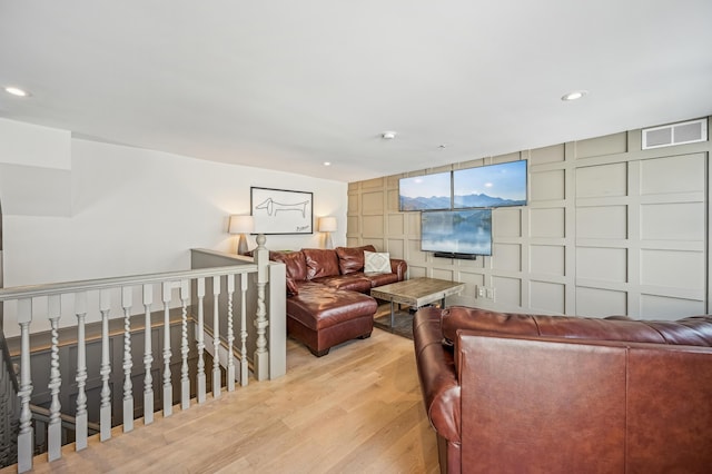 living room featuring a decorative wall, light wood-style floors, and recessed lighting