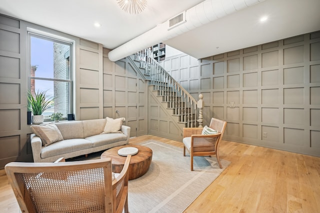 living area featuring stairway, a decorative wall, and light wood-type flooring