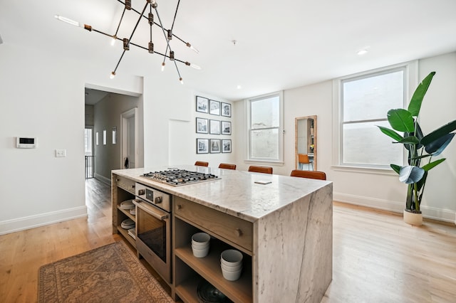 kitchen featuring appliances with stainless steel finishes, open shelves, light stone counters, baseboards, and light wood-style floors