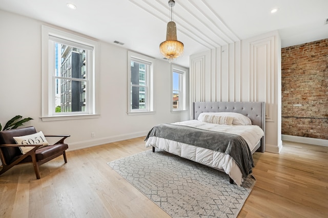 bedroom with baseboards, light wood-type flooring, brick wall, and recessed lighting