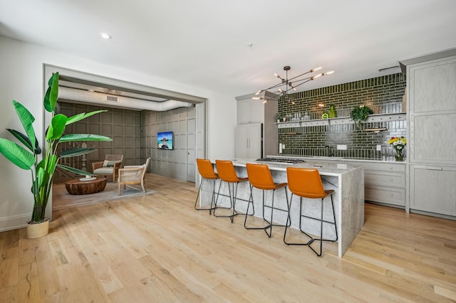 kitchen with light wood-style floors, a breakfast bar, light countertops, and a center island