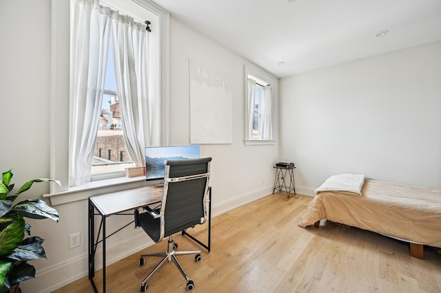 bedroom featuring wood finished floors, baseboards, and a desk