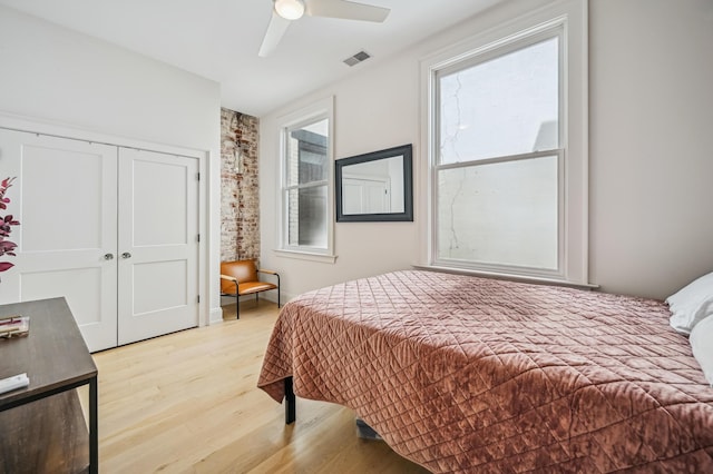 bedroom featuring ceiling fan, light wood-style floors, a closet, and visible vents