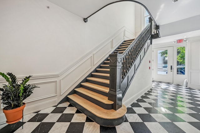 staircase with a decorative wall, plenty of natural light, baseboards, and french doors