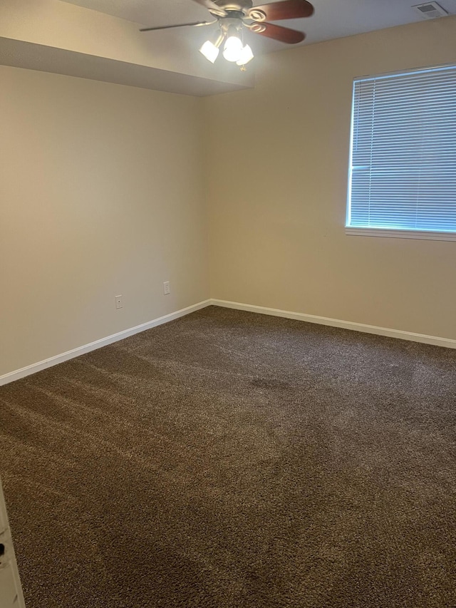 spare room featuring baseboards, a ceiling fan, and dark colored carpet