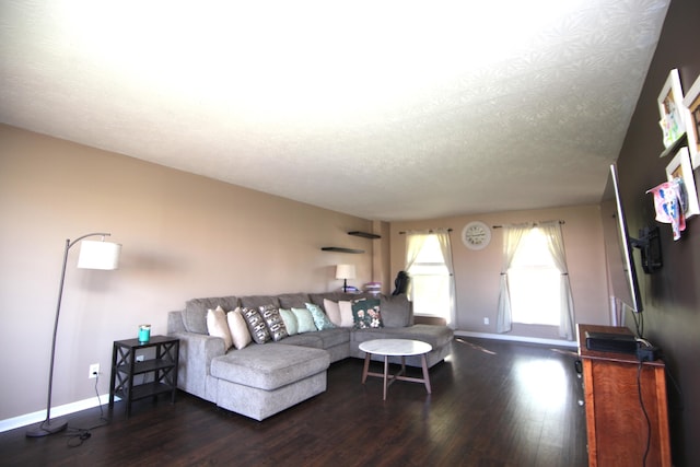 living room with a textured ceiling, baseboards, and wood finished floors