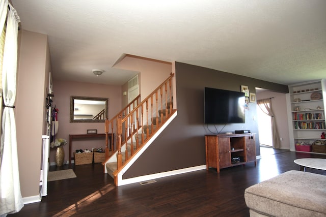 living room with stairs, baseboards, visible vents, and wood finished floors
