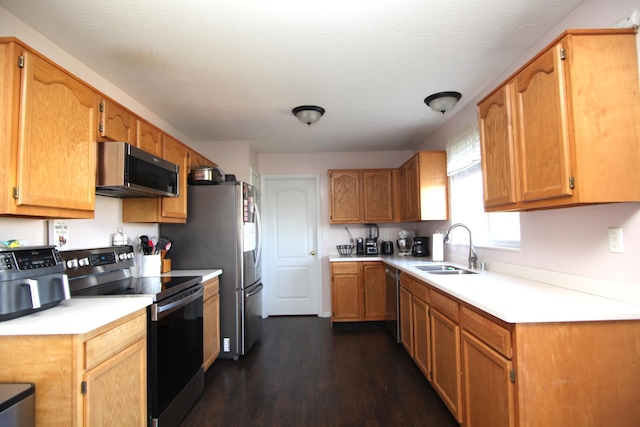 kitchen with dark wood-type flooring, light countertops, brown cabinets, a sink, and stainless steel appliances