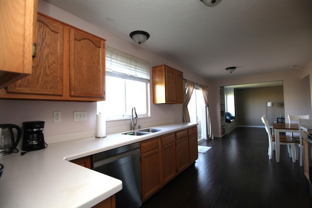 kitchen featuring a sink, dishwasher, light countertops, dark wood finished floors, and brown cabinetry