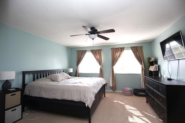 bedroom with a ceiling fan, a textured ceiling, and light carpet