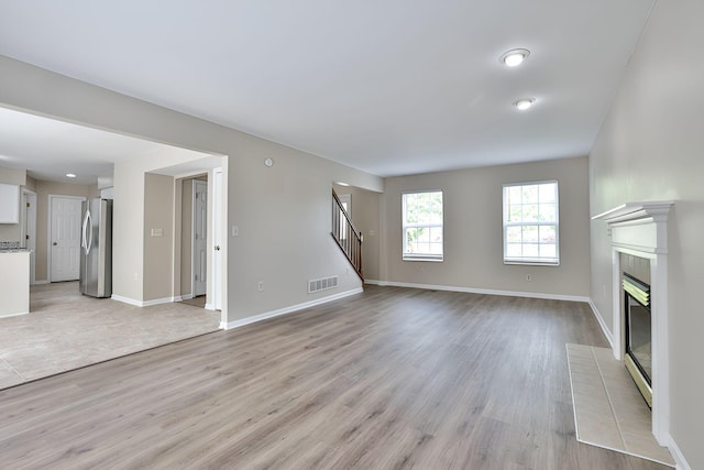 1609 Woodfield Ct, Hebron, KY 41048 - unfurnished living room with stairs, light wood finished floors, and a tiled fireplace