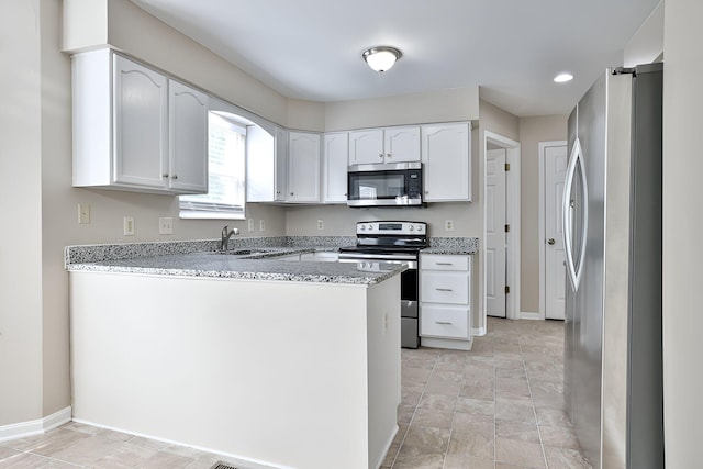 1609 Woodfield Ct, Hebron, KY 41048 - kitchen featuring appliances with stainless steel finishes, a peninsula, white cabinets, light stone counters, and light stone finish floors