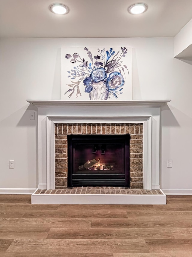 details featuring baseboards, a brick fireplace, recessed lighting, and wood finished floors