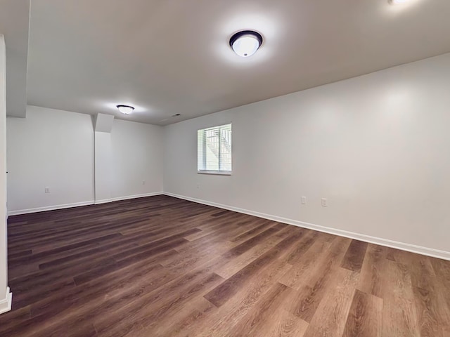 spare room with baseboards and dark wood-style flooring